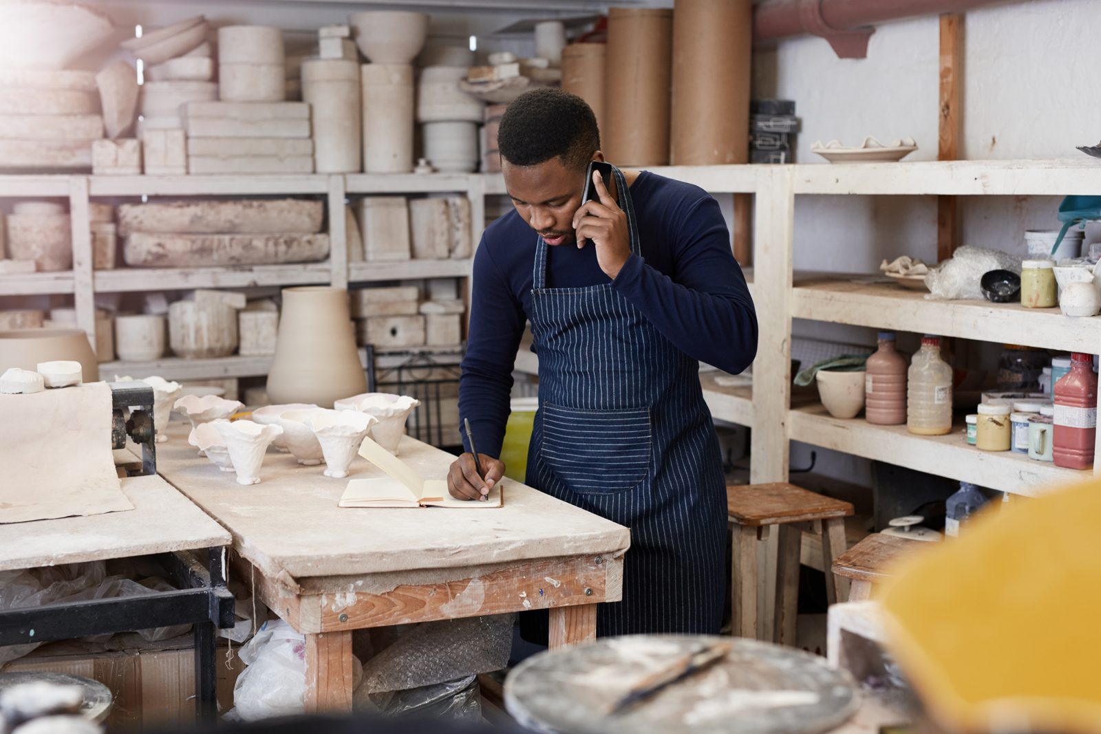 Potter taking a call on his mobile in his workshop